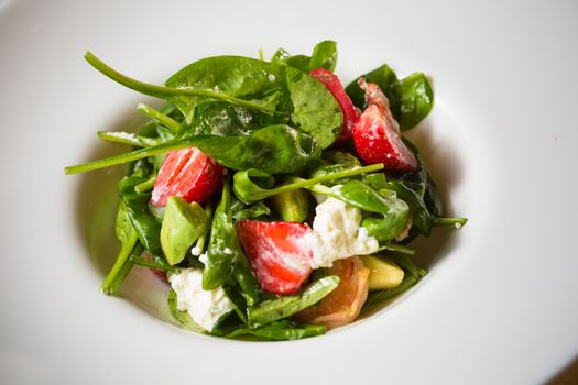 Fresh Salad with strawberries, goat cheese and shrimps dressed with balsamic vinegar and olive oil