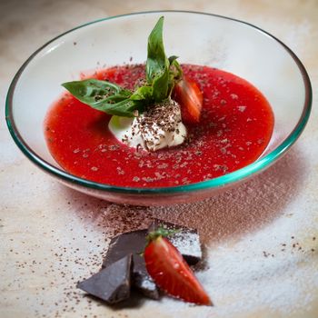 strawberry soup with ice cream and mint on a plate decorated fresh strawberries and chocolate