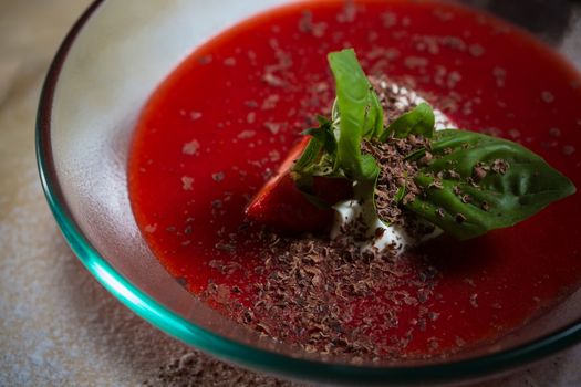 strawberry soup with ice cream and mint on a plate decorated fresh strawberries and chocolate