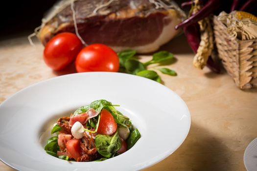 Salad with strawberry, prosciutto, herbs, cottage cheese and blackberry balsamic vinegar. Shallow dof.