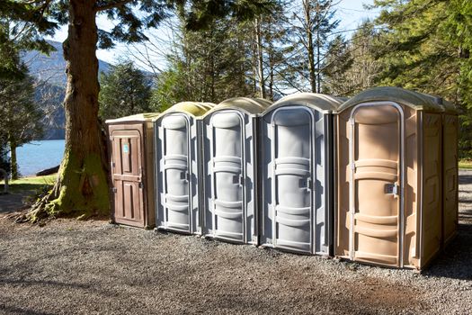 Portapotty, or portable enclosed plastic portable toilet with chemicals and deodorizers in a tank, in a park yard for public convenience