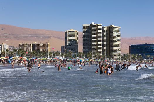 IQUIQUE, CHILE - FEBRUARY 10, 2015: Unidentified people bathing in the Pacific ocean at Cavancha beach on February 10, 2015 in Iquique, Chile. Iquique is a popular beach town and free port city in Northern Chile.