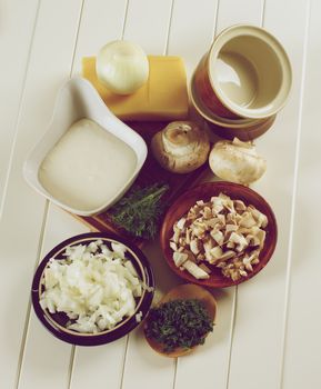 Ingredients of Mushroom Julienne with Raw Chopped Champignon Mushrooms, Onion, Dill with Bechamel and Cheese closeup on Plank White background. Retro Styled