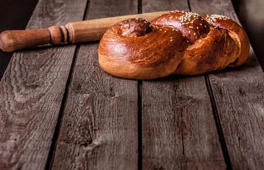 Fresh home-made bread and a rolling pin on a wooden background.