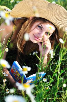 teen girl reading a book on the daisy meadow 