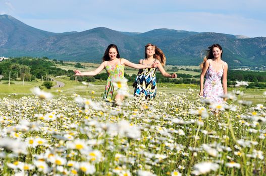 teen happy girls running in daisy field 