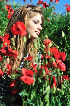 beautiful teen tender girl with long hair sitting in the poppy field 