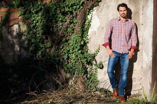 Smiling male model sitting on wooden crate with legs crossed