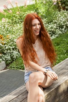 Close up Young Woman with long red Hair Relaxing at the Garden While Looking Afar