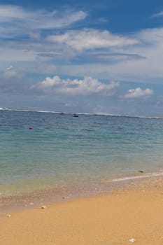 Beautiful tropical beach with lush vegetation fringing golden sand and a tranquil ocean with gentle surf breaking on the beach