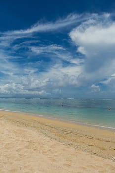 Beautiful tropical beach with lush vegetation fringing golden sand and a tranquil ocean with gentle surf breaking on the beach