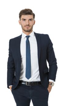 Stylish successful handsome young businessman standing in a relaxed pose with his hands in his pockets and his suit jacket open, isolated on white