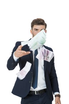 Wealthy successful stylish young businessman burning money from a handful of euro banknotes with a happy smile showing off his affluence, isolated on white