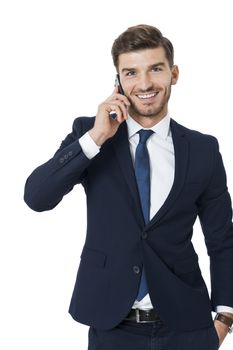 Stylish handsome young businessman chatting on his mobile phone listening to the call with a beaming smile of pleasure, isolated on white