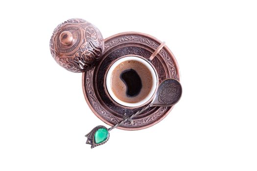 Cup of freshly brewed hot frothy Turkish coffee served in a traditional cup with lid with a decorative teaspoon, overhead view isolated on white