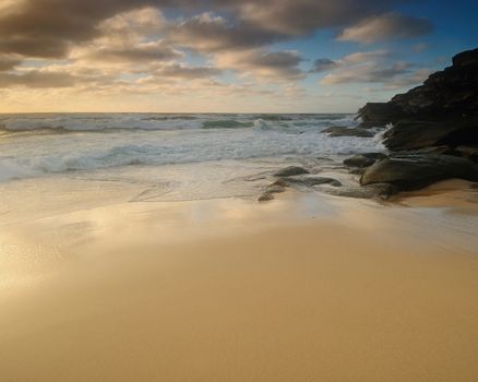 Moody sunrise seascape with colored clouds and flowing water