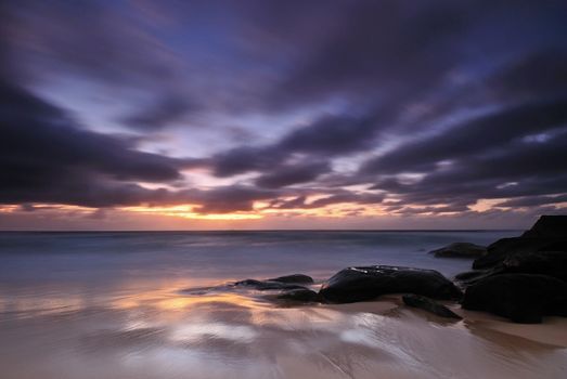 Moody sunrise seascape with colored clouds and flowing water