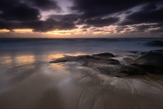 Moody sunrise seascape with colored clouds and flowing water