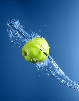 Green apple with water splash on blue water background