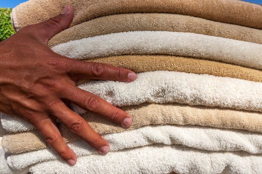 hand on background of stack of white and broun plush hotel towels 
