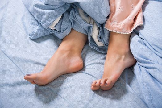 Close up Bare Feet of a Young Woman Lying Down on a Blue Bed, Captured in High Angle View.