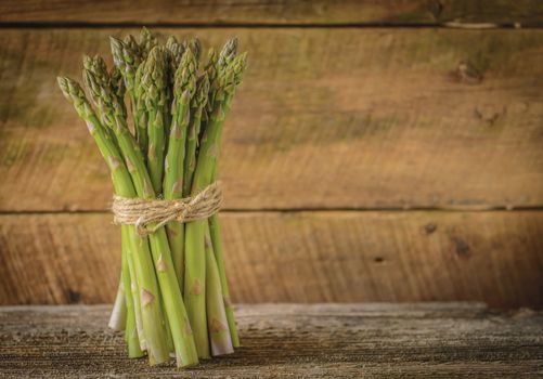 Bunch of fresh asparagus against a rustic wood background.