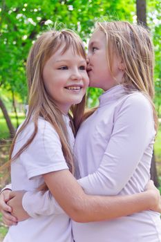 Photo of two smiling whispering girls in summer