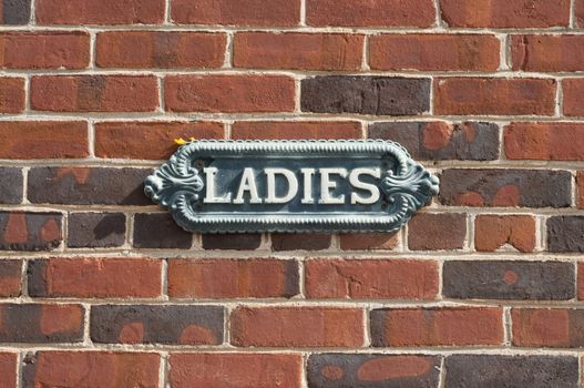 Old antique ladies restroom sign on red brick wall