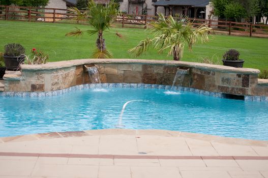 Landscaped swimming pool in residential area with waterfall.