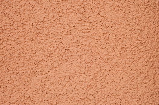 Background of concrete textured wall that is peach in color.