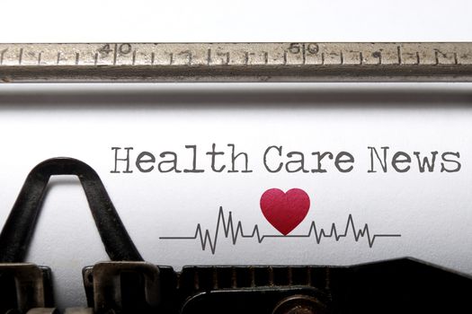 Health care news printed on an old typewriter with heart beat pulse sketch