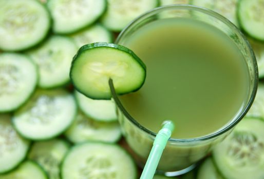 Fresh vegetable detox juice with cucumber slices in the background