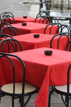 Red table and black chairs on a terrace in Venice
