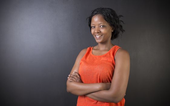 South African or African American woman teacher or student with arms folded on chalk black board background