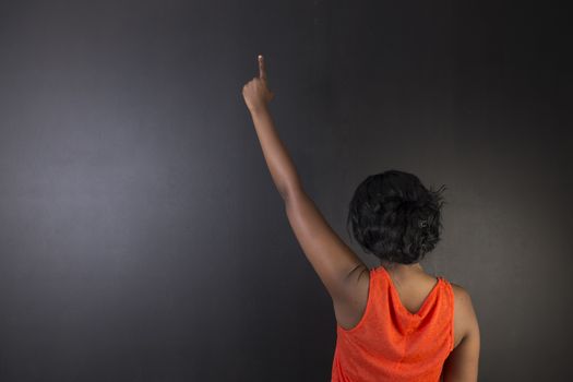South African or African American woman teacher or student with hand up on chalk black board background