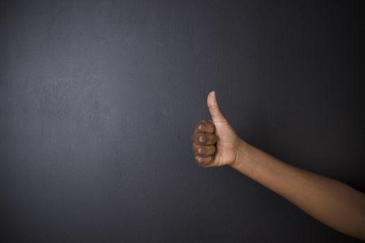 South African or African American woman teacher or student with thumb up on chalk black board background