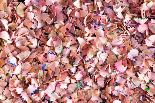 Background texture of colorful wood shavings left behind when sharpening colored pencils crayons for art or school in a random full frame multicolored scatter