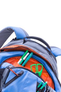 Kids blue and orange school backpack with pens and scissors stowed in the pockets for a creative art class, close up of the pockets and top of the bag over white