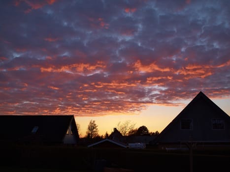 Fiery orange dramatic sunset sky between the houses   