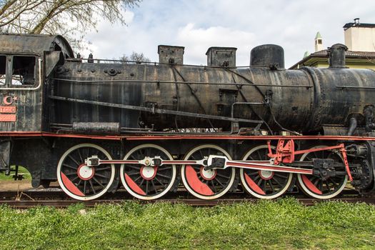 Front view of black old train wagon, in cloudy sky.