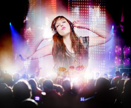 Beautiful woman listening to music with headphones and silhouettes of concert crowd in front of bright stage lights. Concept background of live music and party