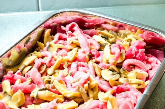 Raw Sliced pork with mushrooms in a baking dish.