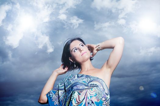 beautiful young woman on a background of sky and clouds expressing purity and freedom. Fashion