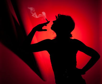 silhouette of woman smoking. Profile of woman pulling smoke on red background. Fashion