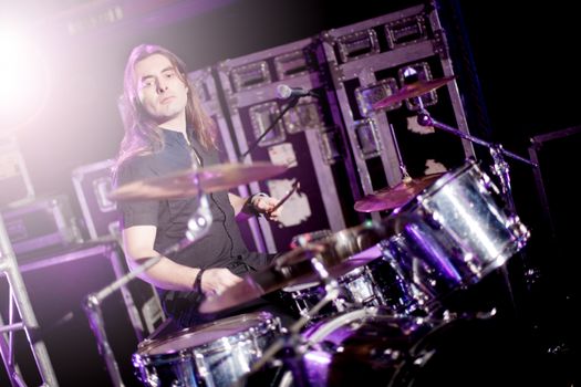 Man playing drums live with stage lights. Live music concept