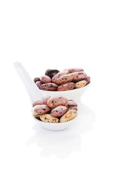 Pinto beans on white spoon isolated on white background. Healthy legume eating. Fresh modern image language. Culinary arts. 