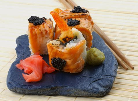 Arrangement of Maki Sushi with Salmon, Crab, Shrimp and Black Caviar on with Chopsticks, Ginger and Wasabi on Black Stone Plate. Top View