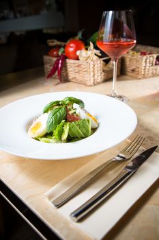 Closeup of plate of spring mix salad with strawberry, eggs and tuna