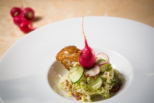Salad from cabbage, herbs, cucumber, onion and radish in bowl on green wooden background. Coleslaw. Selective focus.