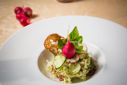 Salad from cabbage, herbs, cucumber, onion and radish in bowl on green wooden background. Coleslaw. Selective focus.